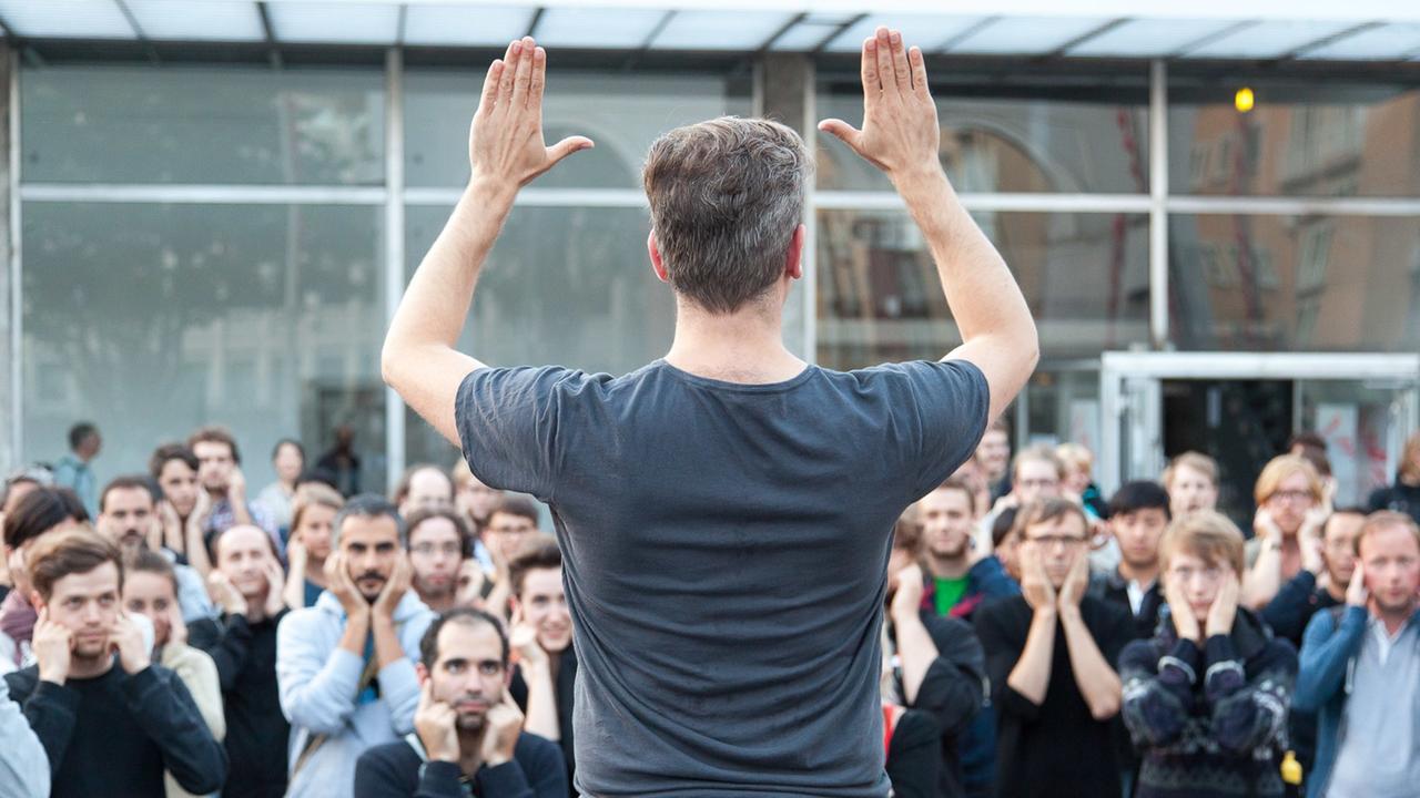 Ein Mann animiert das Publikum, Gesten und Laute nachzumachen Ein Mann animiert das Publikum, Gesten und Laute nachzumachen