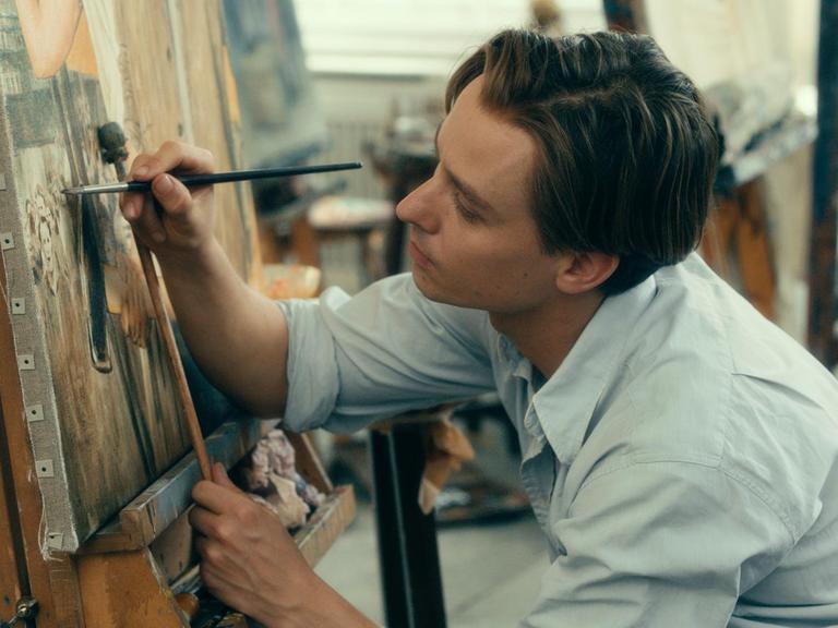 Tom Schilling vor einer Leinwand mit einem Pinsel in der Hand. Szene aus dem Film "Werk ohne Autor".