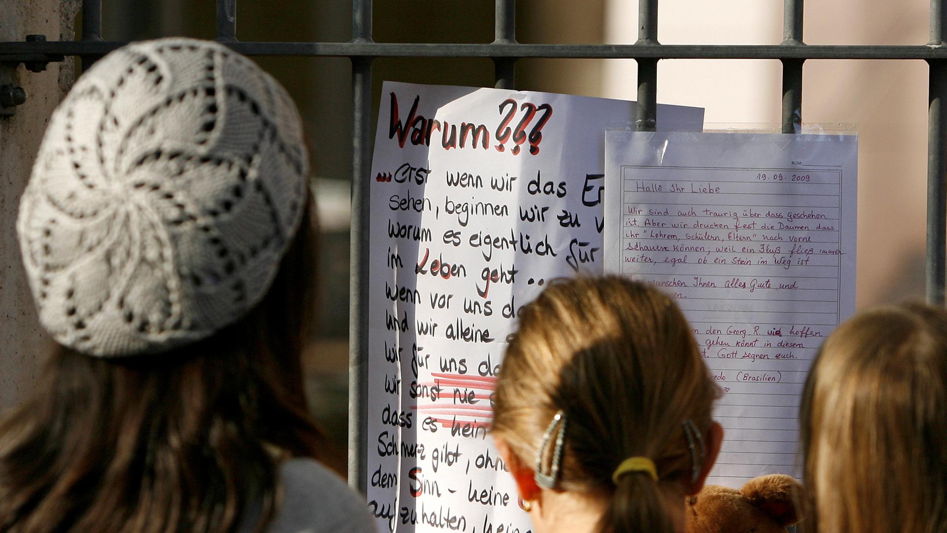 Jugendliche betrachten an einem Schultor einen Zettel mit dem Titel "Warum???" Jugendliche betrachten an einem Schultor einen Zettel mit dem Titel "Warum???"