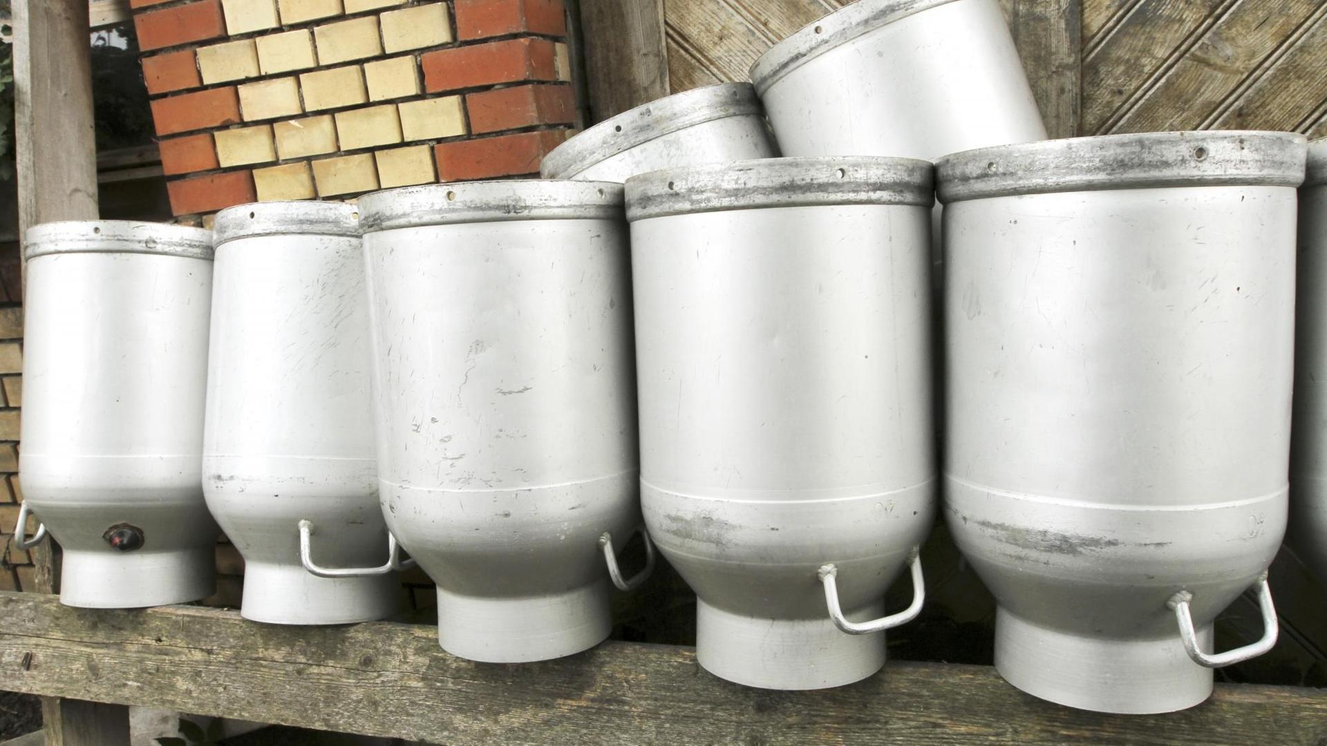Mehrere umgedrehte Milchkannen sind auf einer Ablage gestellt. Mehrere umgedrehte Milchkannen sind auf einer Ablage gestellt.