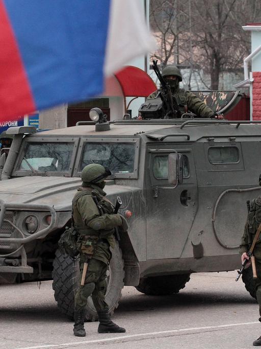 Soldaten der Ukraine haben Stellung bezogen vor einem Panzer und der Fahne des Landes in Balaklava auf der Krim.