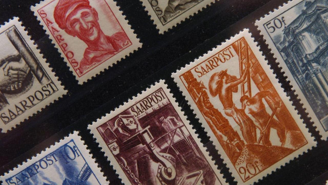 Sieben Briefmarken der Saarpost auf schwarzem Hintergrund.