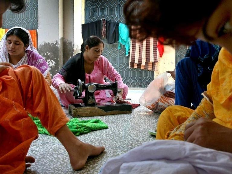 Frauen sitzen in einem Raum, in dem sie vor Männergewalt in Pakistan geschützt werden sollen