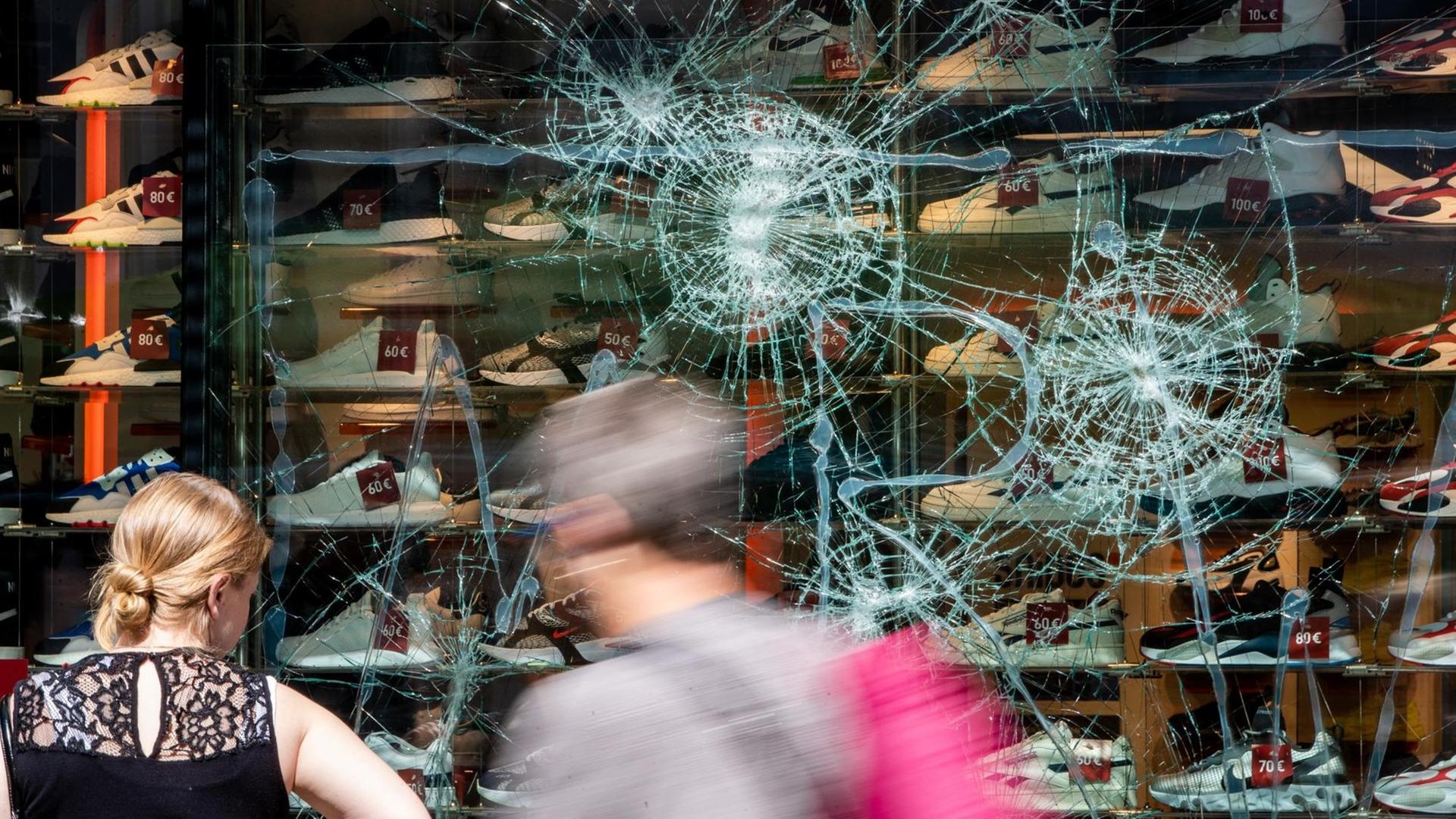 Fußgänger stehen beschädigten Schau-Fenster in Stuttgart. Fußgänger stehen beschädigten Schau-Fenster in Stuttgart.