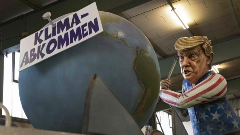 Eine Figur von Donald Trump greift den Globus an. Eine Figur von Donald Trump greift den Globus an.