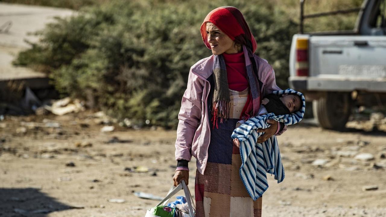 Eine Syrerin flieht aus der Kampfzone zwischen türkisch geführten Truppen und kurdischen Kämpfern der syrisch-demokratischen Kräfte (SDF) Eine Syrerin flieht aus der Kampfzone zwischen türkisch geführten Truppen und kurdischen Kämpfern der syrisch-demokratischen Kräfte (SDF)