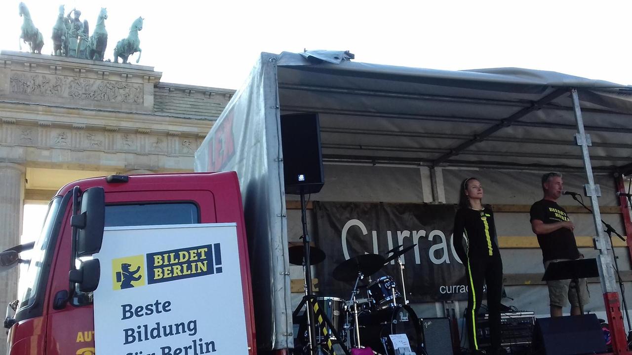 Auf der Ladefläche eines Lastwagens stehen ein Mann und eine Frau am Mikrofon. Auf der Ladefläche eines Lastwagens stehen ein Mann und eine Frau am Mikrofon.