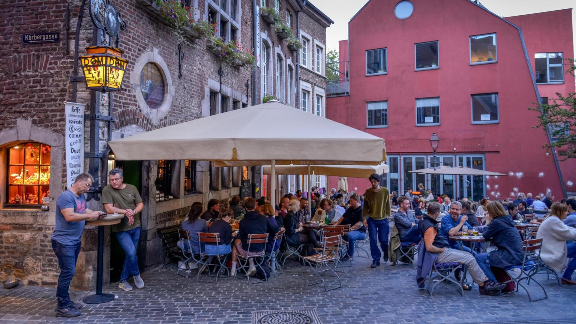 Menschen sitzen an Tischen vor einem Restauran. Menschen sitzen an Tischen vor einem Restauran.