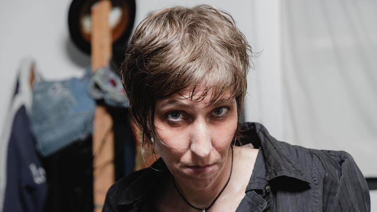 Eine Frau mit mittellangen, strähnigen dunkelblonden Haaren trägt ein dunkles Oberteil und blickt von unten in die Kamera. Eine Frau mit mittellangen, strähnigen dunkelblonden Haaren trägt ein dunkles Oberteil und blickt von unten in die Kamera.