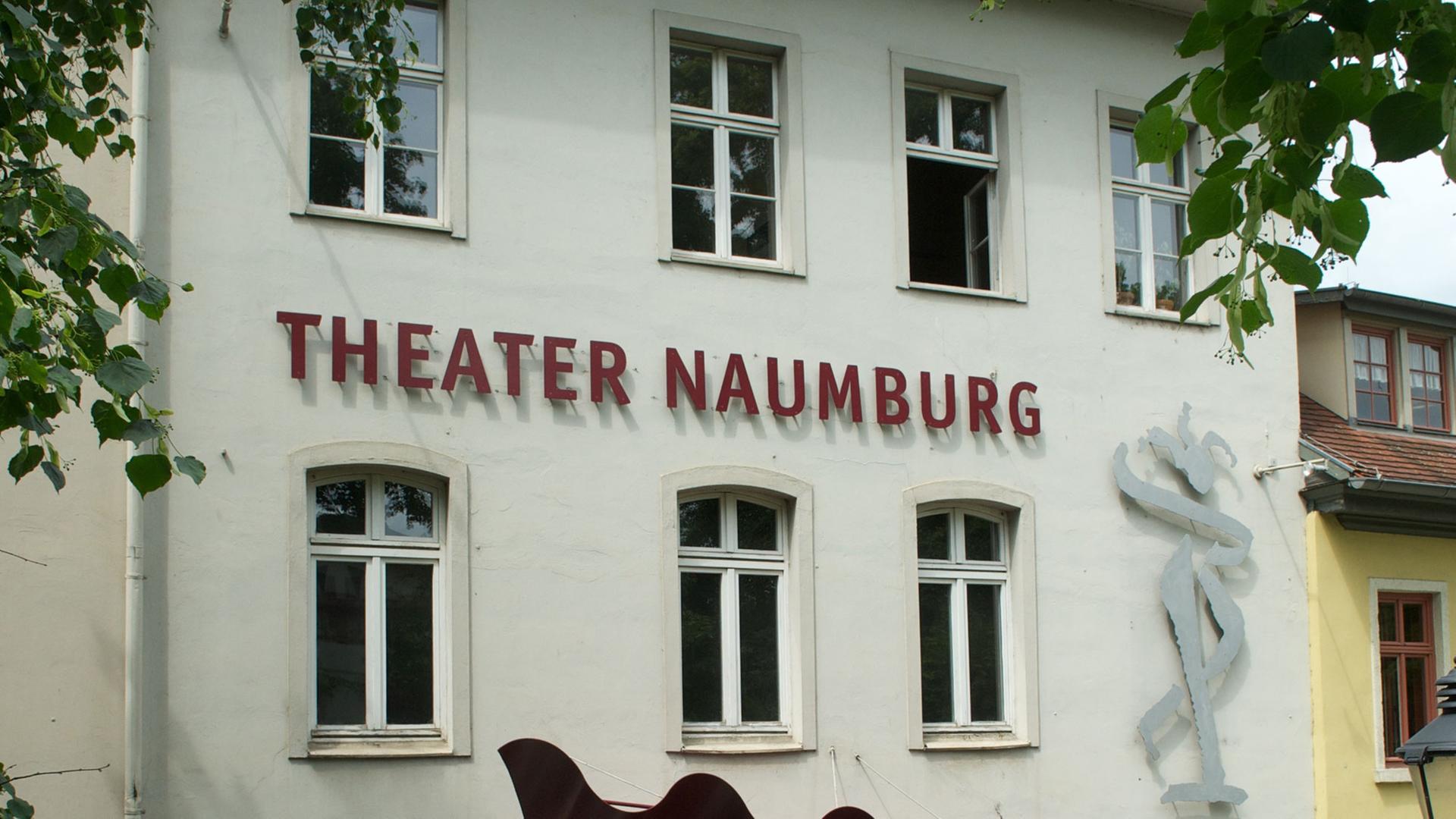 Weiße Hausfassade eines Altbaus, Theater Naumburg steht darauf in roten Blechbuchstaben, das Gebäude ist von grünen Blättern umrankt Weiße Hausfassade eines Altbaus, Theater Naumburg steht darauf in roten Blechbuchstaben, das Gebäude ist von grünen Blättern umrankt