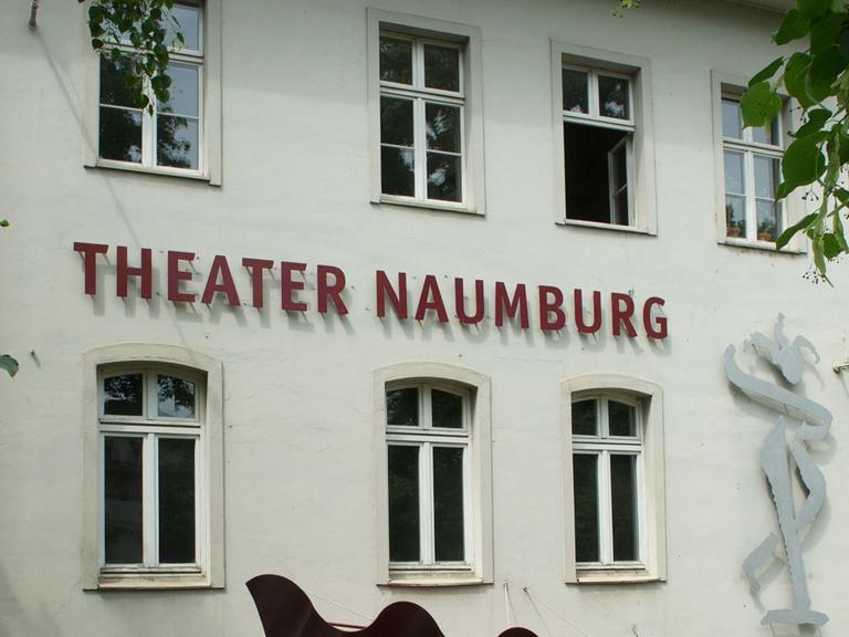 Weiße Hausfassade eines Altbaus, Theater Naumburg steht darauf in roten Blechbuchstaben, das Gebäude ist von grünen Blättern umrankt