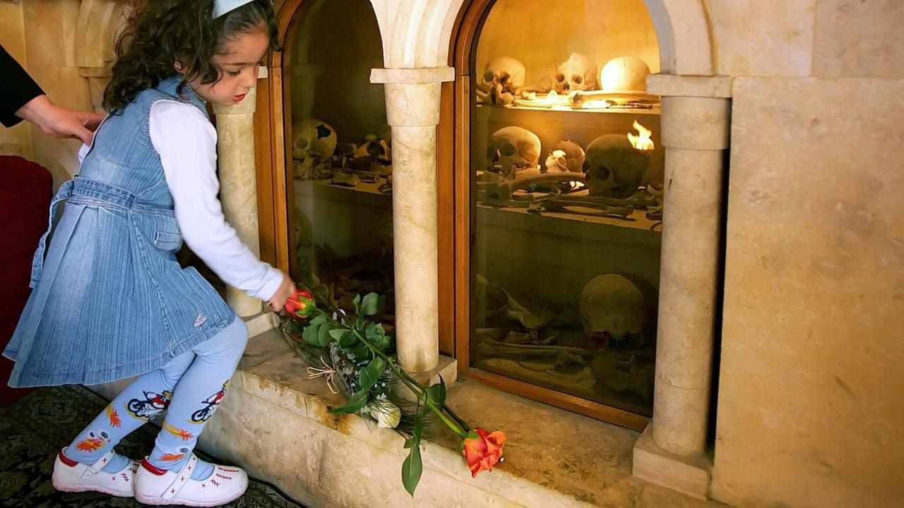 Ein amenisches Kind legt in einer Kirche im Libanon eine Rose vor einem Schrein mit Totenköpfen der Opfer nieder. Ein amenisches Kind legt in einer Kirche im Libanon eine Rose vor einem Schrein mit Totenköpfen der Opfer nieder.
