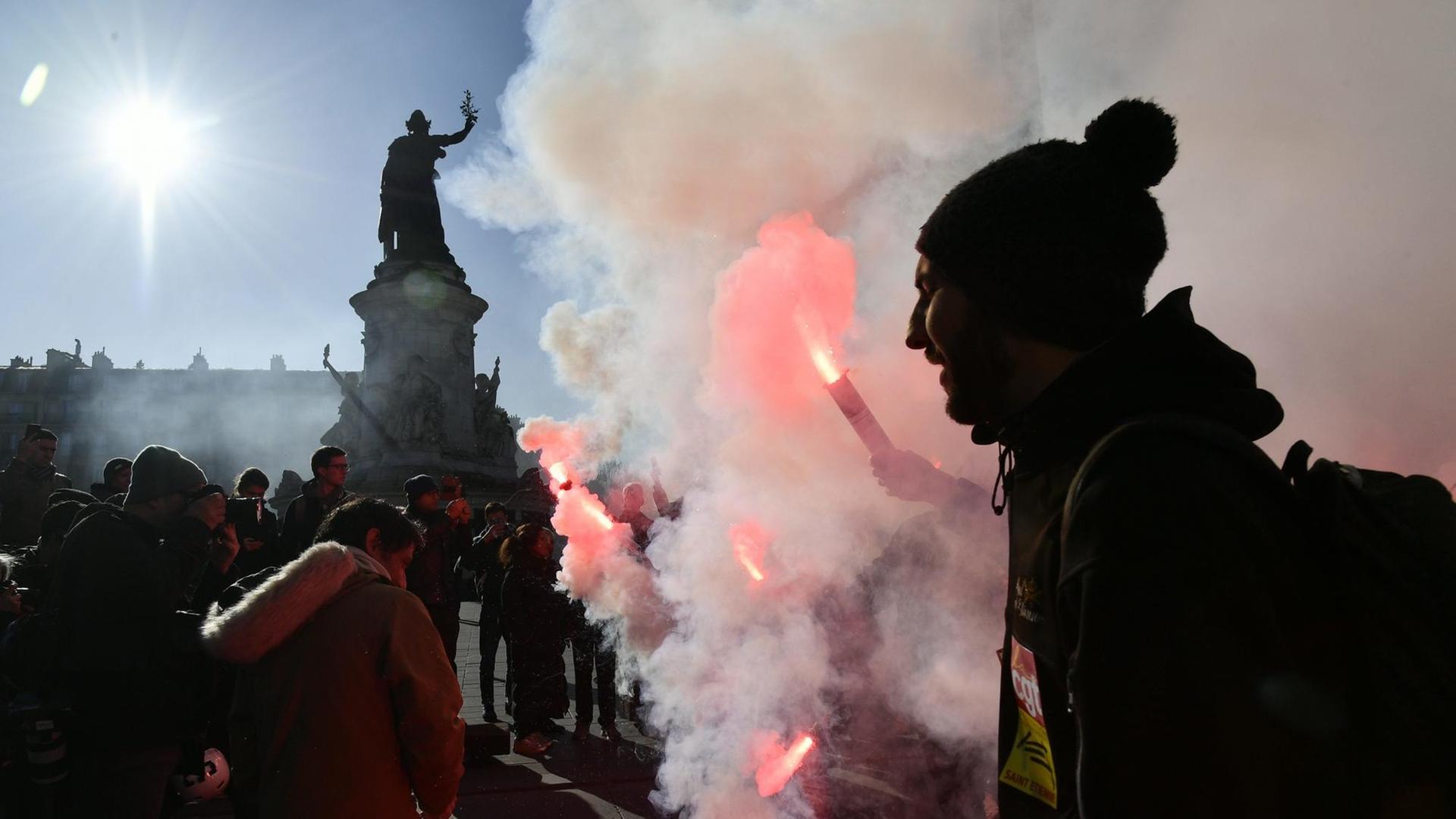 Demonstranten halten bei Protesten gegen Macrons Rentenreform Pyrotechnik in der Hand.