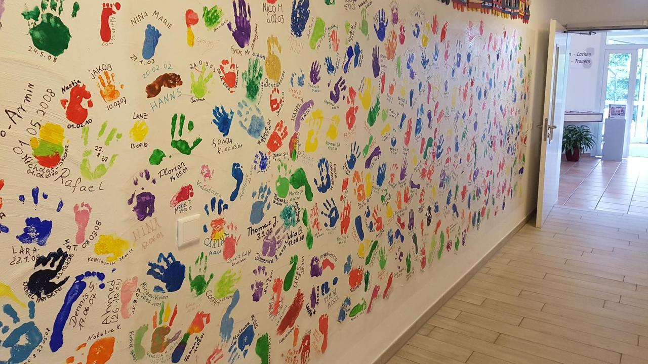 Eine Wand mit bunten Hand und Fußabdrücken der Kinder