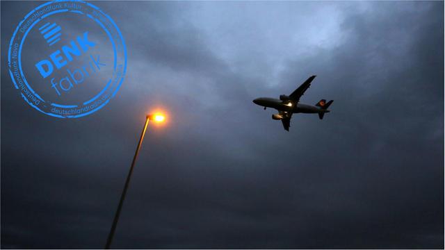 Ein Flugzeug landet in Frankfurt. Im Vordergrund eine Lampe. Ausgezeichnet mit dem Stempel der Denkfabrik