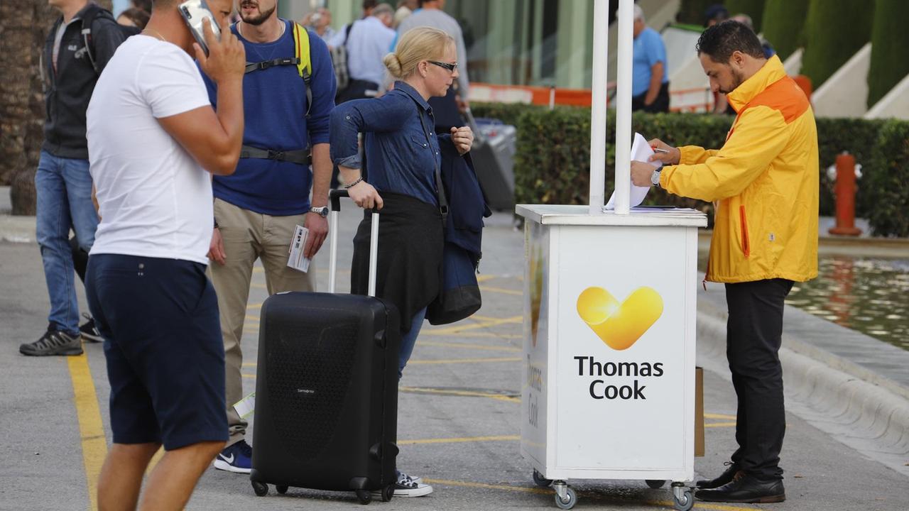 Passagiere stehen am Flughafen Palma de Mallorca am Tag des Scheiterns von Thomas Cook an einem Informationsschalter. Passagiere stehen am Flughafen Palma de Mallorca am Tag des Scheiterns von Thomas Cook an einem Informationsschalter.