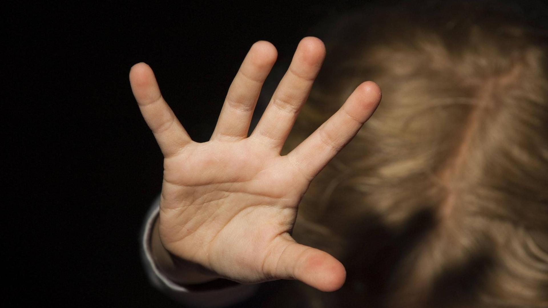 Ein Kind streckt die Hand zur Abwehr nach oben. Ein Kind streckt die Hand zur Abwehr nach oben.