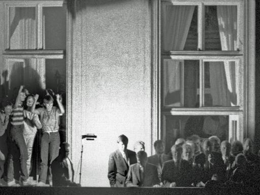 Bundesaußenminister Hans-Dietrich Genscher (Mitte vor dem Fensterkreuz rechts) verkündet am 30.09.1989 kurz vor 19 Uhr auf dem Balkon der Deutschen Botschaft in Prag: "Wir sind heute zu Ihnen gekommen, um Ihnen mitzuteilen, dass heute Ihre Ausreise....". Der weitere Wortlaut der Ankündigung der bechlossenen Ausreise der DDR-Flüchtlinge, die im Hof der Botschaft campierten, ging in tosendem Jubel unter.