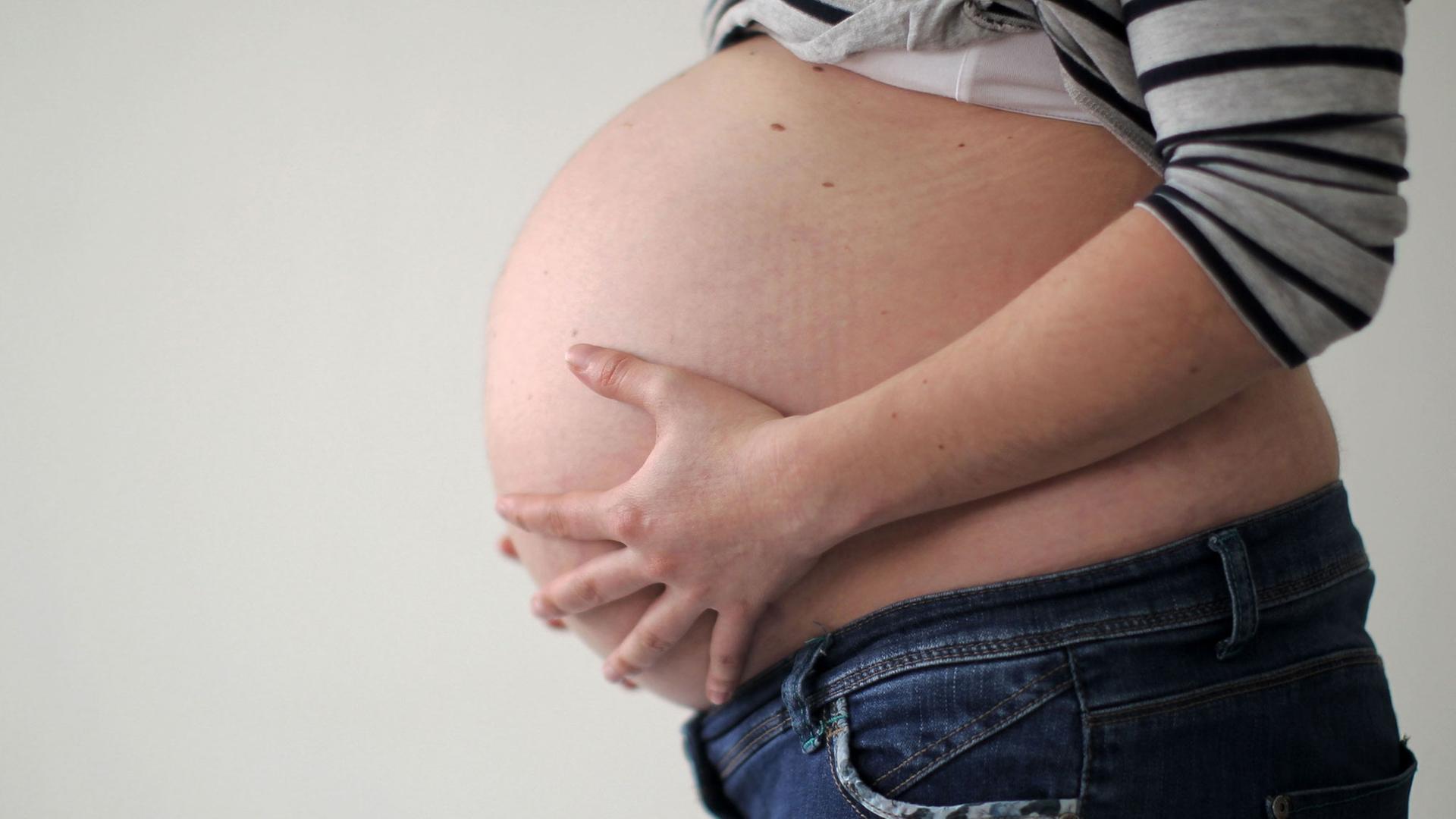 Eine schwangere Frau hält ihren Bauch. Eine schwangere Frau hält ihren Bauch.