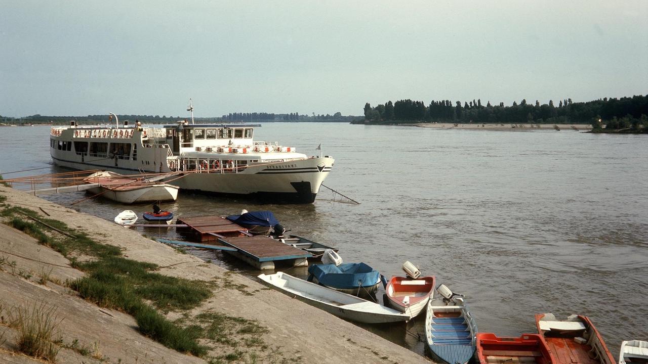 Blick über Boote auf einen Ausflugsdampfer auf dem Po bei Cremona in der Lombardei. 