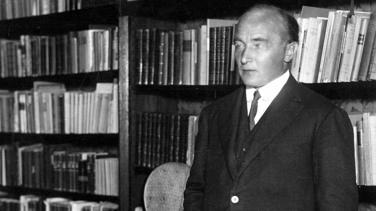 Robert Musil steht vor einem Buchregal Robert Musil steht vor einem Buchregal