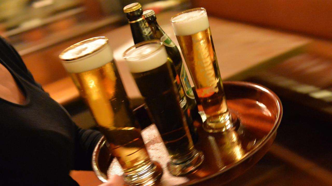 Eine Bedienung trägt am 29.10.2013 in Erfurt (Thüringen) in einem Lokal ein Tablett mit Bier. Der Mindestlohn gilt auch im Hotel- und Gaststättengewerbe. Eine Bedienung trägt am 29.10.2013 in Erfurt (Thüringen) in einem Lokal ein Tablett mit Bier. Der Mindestlohn gilt auch im Hotel- und Gaststättengewerbe.