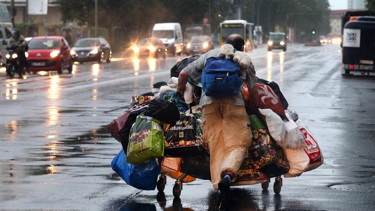 Ein Obdachloser versucht sein Hab und Gut vor dem Starkregen in Sicherheit zu bringen am 22.07.2017 in Berlin, Storkower Straße.