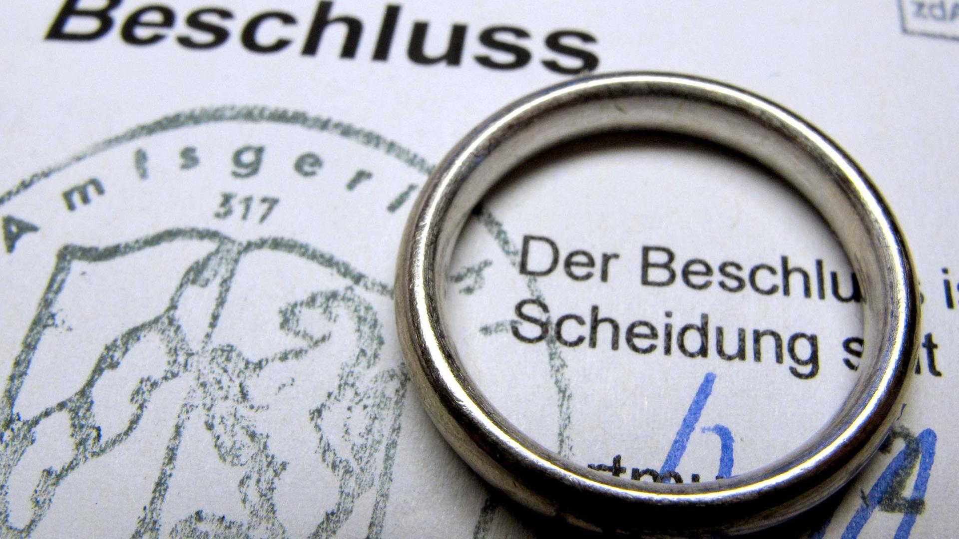 Ein Ehering liegt auf einem Gerichtsbeschluss über eine rechtskräftige Scheidung. Ein Ehering liegt auf einem Gerichtsbeschluss über eine rechtskräftige Scheidung.