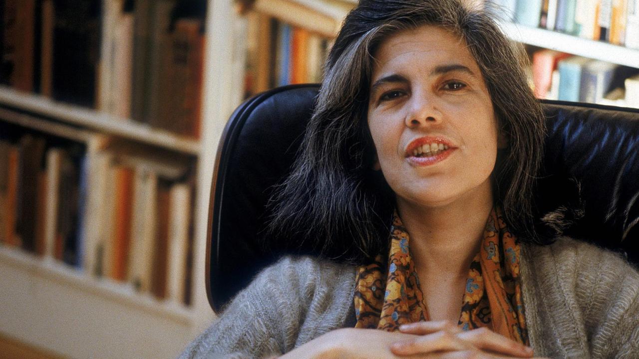 Susan Sontag in einem Sessel vor Bücherregalen. Susan Sontag in einem Sessel vor Bücherregalen.