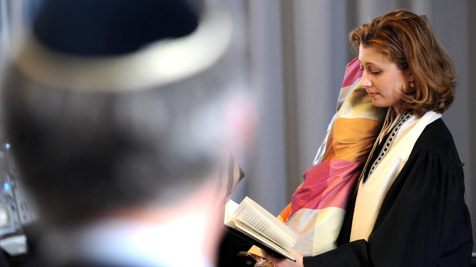 Die Rabbinerin in Oldenburg, Alina Treiger, hält am Sonntag (27.03.2011) zu ihrer offiziellen Amtseinführung im Kulturzentrum PFL in Oldenburg die Tora-Rolle im Arm und liest ein Gebet vor. Die Rabbinerin in Oldenburg, Alina Treiger, hält am Sonntag (27.03.2011) zu ihrer offiziellen Amtseinführung im Kulturzentrum PFL in Oldenburg die Tora-Rolle im Arm und liest ein Gebet vor.