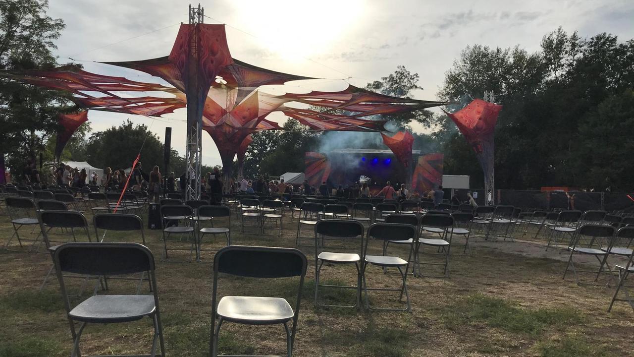 Das "Goa Nature"-Festival 2020, Blick auf Stuhreihen unter freiem Himmel, im Hintergrund Publikum und eine Bühne Das "Goa Nature"-Festival 2020, Blick auf Stuhreihen unter freiem Himmel, im Hintergrund Publikum und eine Bühne