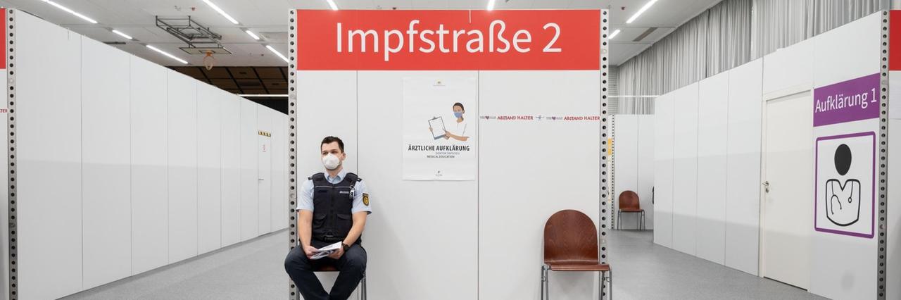 Ein Polizeibeamter wartet in einem Impfzentrum auf seine Corona-Impfung. Ein Polizeibeamter wartet in einem Impfzentrum auf seine Corona-Impfung.