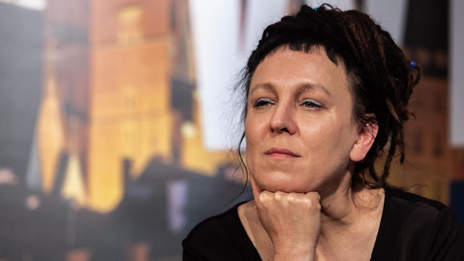 Olga Tokarczuk sitzt auf einem Podium und hört den Fragen zu. Olga Tokarczuk sitzt auf einem Podium und hört den Fragen zu.