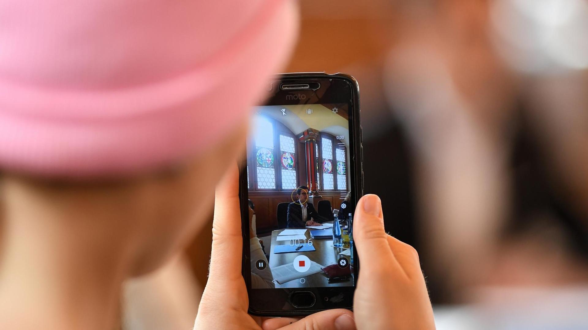 Eine Journalistin macht während einer Pressekonferenz mit ihrem Smartphone ein Foto. Eine Journalistin macht während einer Pressekonferenz mit ihrem Smartphone ein Foto.