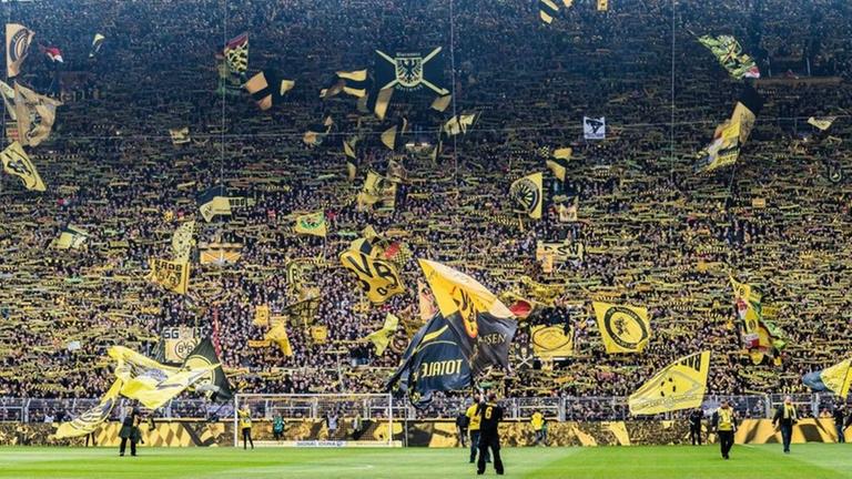 ARCHIV - Dicht gedrängt stehen Fans des Fußballclubs Borussia Dortmund am 27. April 2019 in der sogenannten Gelben Wand, der Südtribüne des Stadions schwenken gelbe Fahne und Schals. ARCHIV - Dicht gedrängt stehen Fans des Fußballclubs Borussia Dortmund am 27. April 2019 in der sogenannten Gelben Wand, der Südtribüne des Stadions schwenken gelbe Fahne und Schals.