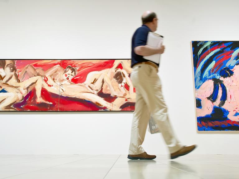 Ein Mann blickt am 21.07.2015 in der Kunstausstellung "Die 80er. Figurative Malerei in der BRD" im Städel Museum in Frankfurt am Main auf die Kunstwerke "Babylon" (l) und "Sumokämpfer blau" von dem Berliner Maler Salomé.