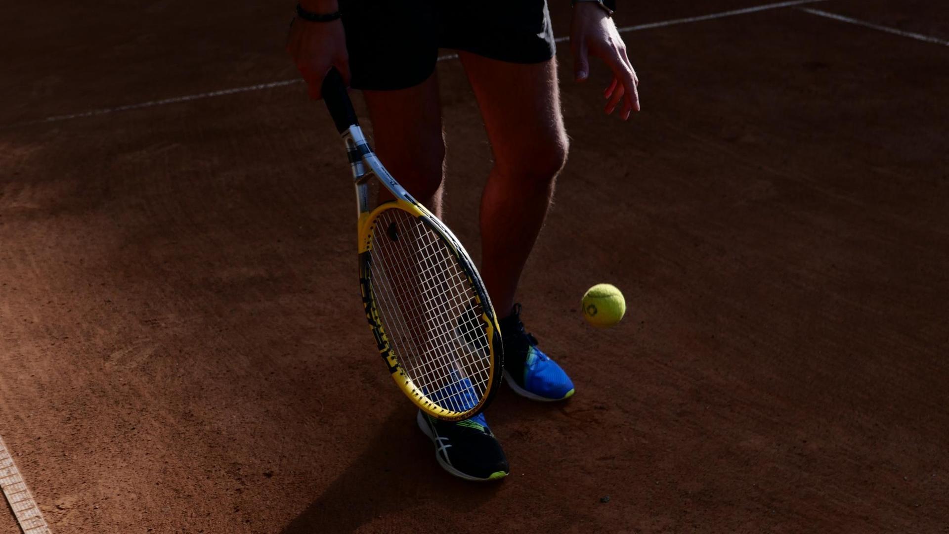 Ausschnitt eines Tennisspielers mit Schläger und Ball, der vom Sonnenlicht gestriffen wird. Ausschnitt eines Tennisspielers mit Schläger und Ball, der vom Sonnenlicht gestriffen wird.