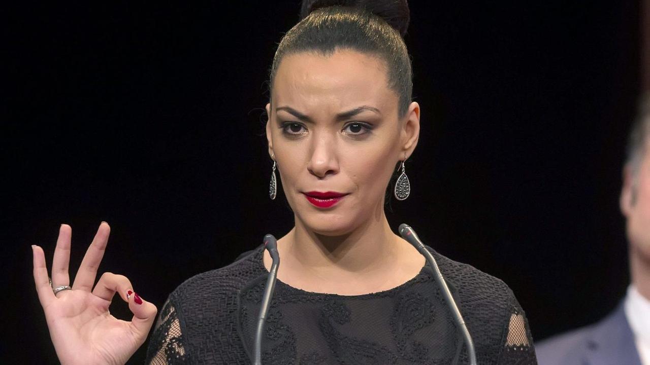 Eine aparte, schöne junge Frau mit hochgestecktem Pferdeschwanz hält eine Rede auf einer glamourösen Veranstaltung. Eine aparte, schöne junge Frau mit hochgestecktem Pferdeschwanz hält eine Rede auf einer glamourösen Veranstaltung.