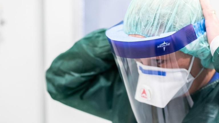 28.02.2020, Nordrhein-Westfalen, Essen: Canan Emcan, Stationsleiterin auf der Infektionsstation der Uniklinik Essen, steht in Schutzkleidung und mit einer Atemmaske in einer Schleuse und bekleidet sich mit einem Gesichtsschutz. Hier werden besonders schwere Fälle behandelt und hier könnten in Zukunft auch Coronavirus-Patienten untergebracht werden. Foto: Marcel Kusch/dpa | Verwendung weltweit 28.02.2020, Nordrhein-Westfalen, Essen: Canan Emcan, Stationsleiterin auf der Infektionsstation der Uniklinik Essen, steht in Schutzkleidung und mit einer Atemmaske in einer Schleuse und bekleidet sich mit einem Gesichtsschutz. Hier werden besonders schwere Fälle behandelt und hier könnten in Zukunft auch Coronavirus-Patienten untergebracht werden. Foto: Marcel Kusch/dpa | Verwendung weltweit
