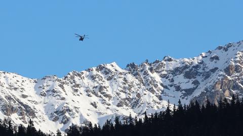 Zwei Hubschrauber im Anflug auf Davos, im Hintergrund schneebedeckte Berge.