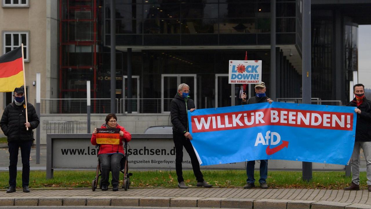 AfD-Anhänger stehen bei einer Demonstration mit einem Banner "Willkür beenden" vor dem Sächsischen Landtag in Dresden.