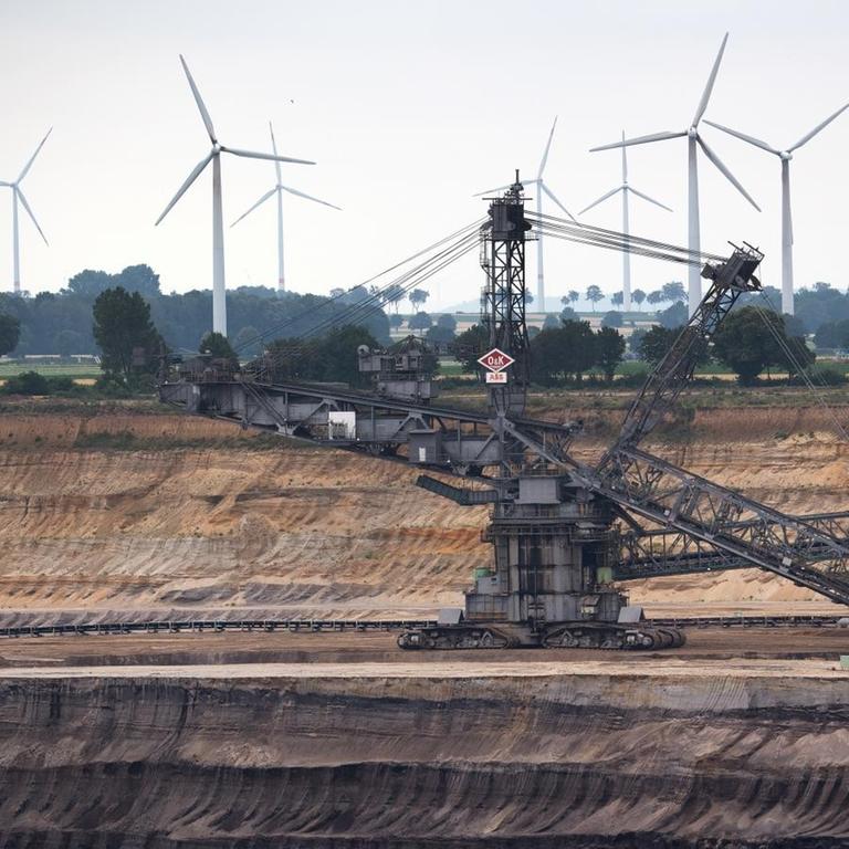 03.07.2020, Nordrhein-Westfalen, Jackerath: Hinter einem Schaufelradbagger im Braunkohletagebau Garzweiler drehen sich Windräder zur Stromerzeugung. Bundestag und Bundesrat wollen den schrittweisen Kohleausstieg in Deutschland bis spätestens 2038 beschließen. Am Vormittag stimmt zunächst der Bundestag über zwei zentrale Gesetze ab, danach folgt die Länderkammer. Foto: Federico Gambarini/dpa | Verwendung weltweit