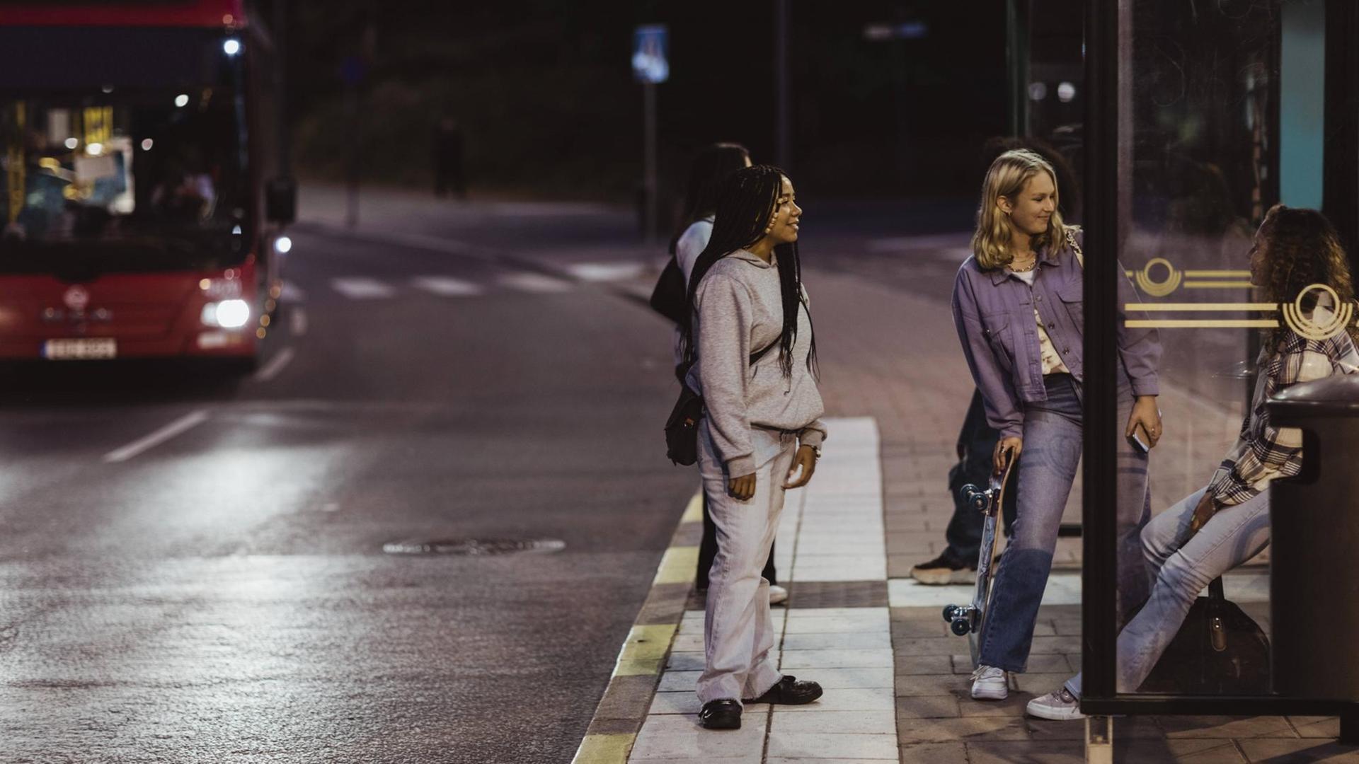 Freundinnen stehen in der Nacht an einer Bushaltestelle auf dem Nachhauseweg. (Symbolbild)