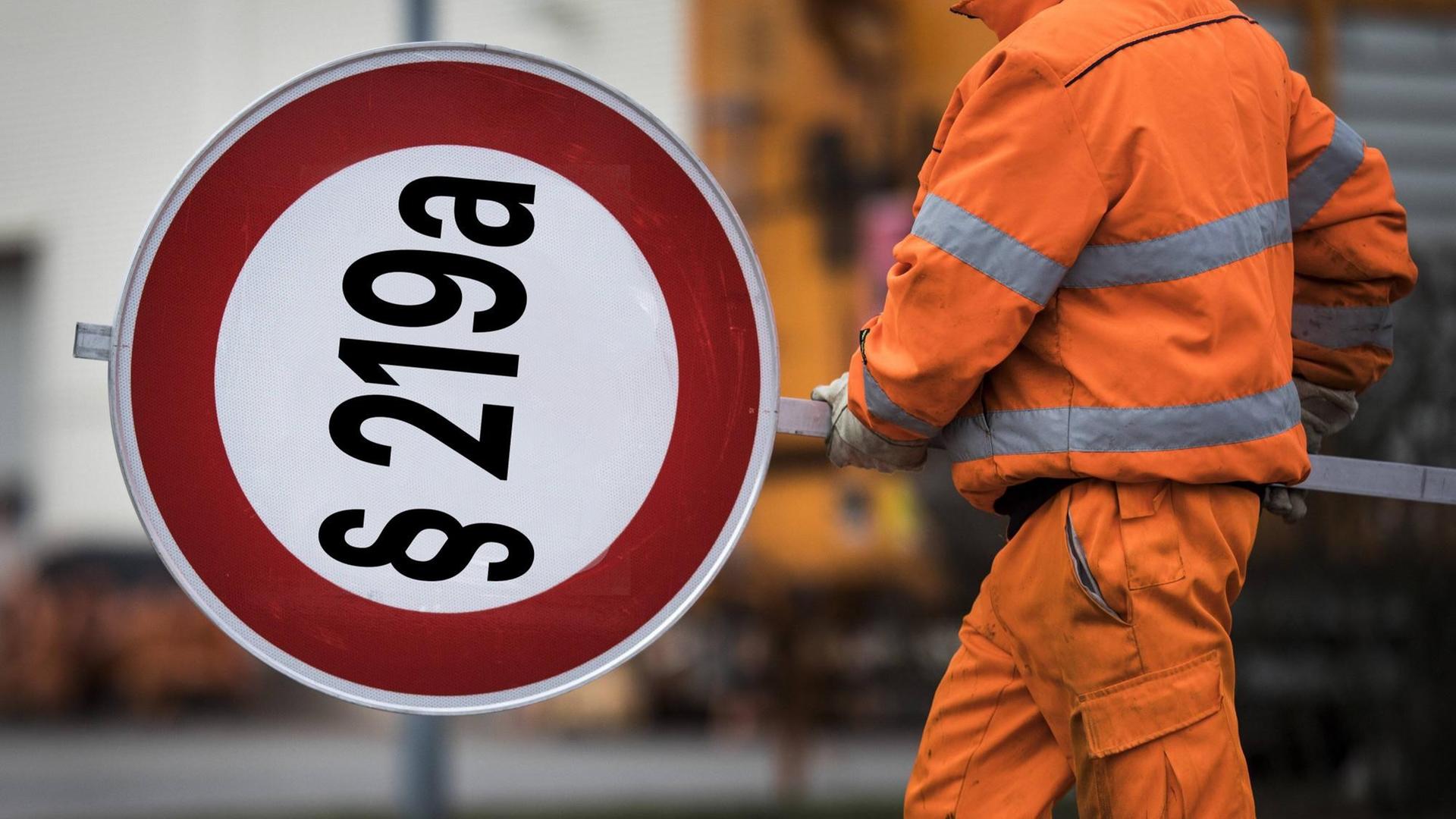 Ein Mitarbeiter der Autobahnmeisterei mit einem Schild auf den "§ 219a" montiert ist. Ein Mitarbeiter der Autobahnmeisterei mit einem Schild auf den "§ 219a" montiert ist.
