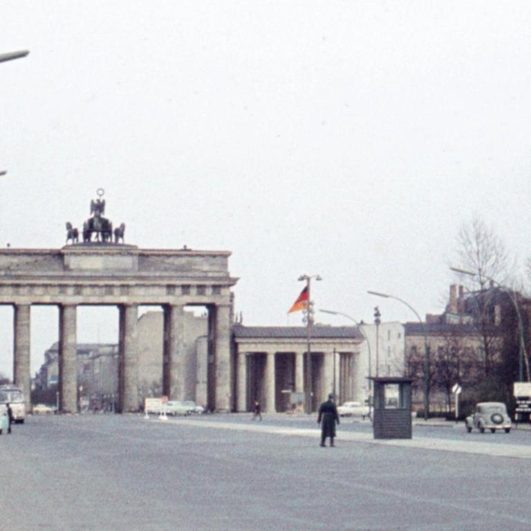 Blasse historische Fotografie aus dem Jahr 1961 vom Platz vor dem Brandenburger Tor, auf dem ein Wachhäuschen platziert ist.