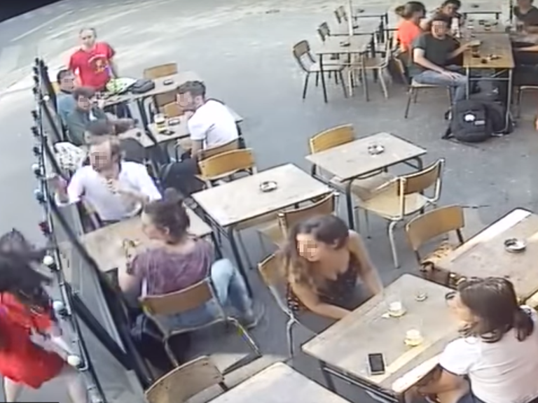 Das Bild zeigt, wie eine Frau von einem Mann vor Zeugen ins Gesicht geschlagen wird.