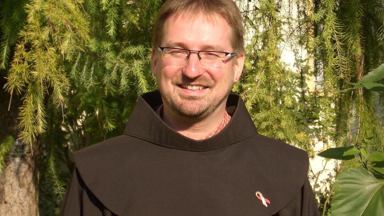 Der Franziskaner Bruder Andreas trägt Kutte und schaut freundlich in die Kamera. Der Franziskaner Bruder Andreas trägt Kutte und schaut freundlich in die Kamera.