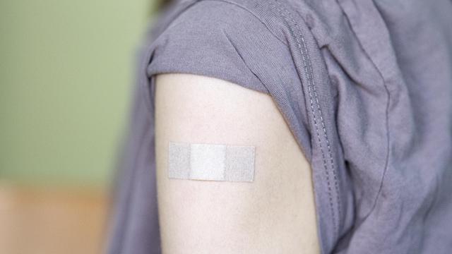 Auf dem Arm eines Jugendlichen klebt ein Pflaster, nachdem er bei einem Kinder- und Jugendarzt geimpft wurde.