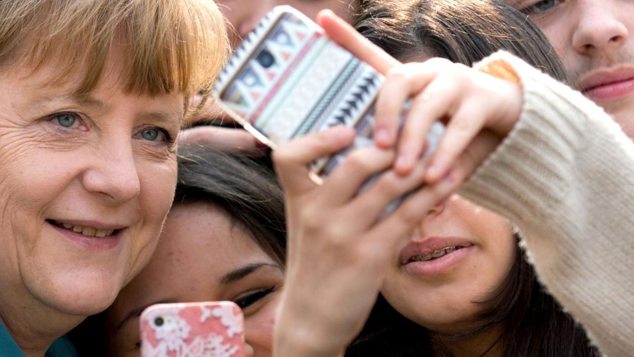 Jugendliche fotografieren Bundeskanzlerin Angela Merkel mit ihrem Smartphone (2014)