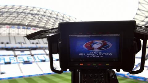 Auf dem Kamera-Bildschirm sieht man das Logo der Europaameisterschaft. Im Hintergrund sieht man eine Tribüne mit der Aufschrift "Marseille".